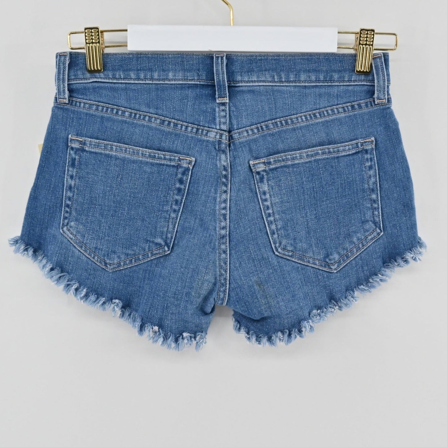 Lynn's Closet Boutique L'Agence Zoe medium-blue denim cut-off shorts with raw-edge hem and five-pocket styling.