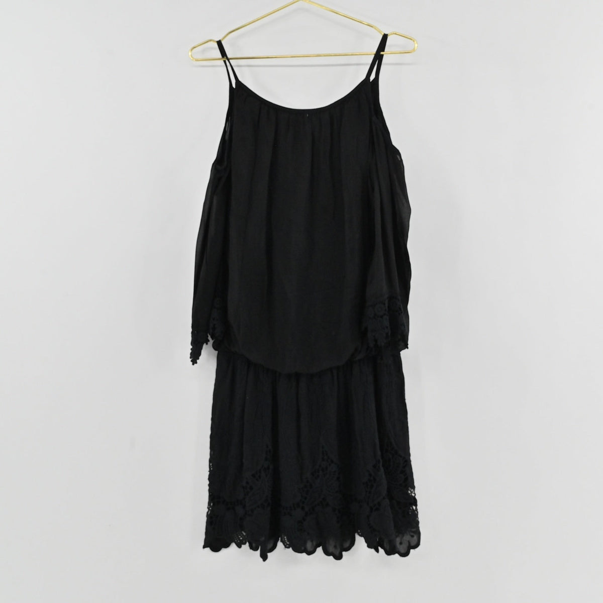 Lynn's Closet Boutique black cold-shoulder dress with delicate lace trim on sleeves and hem hanging on a gold hanger
