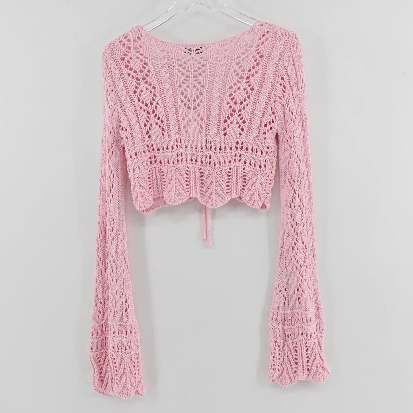 Lynn's Closet Boutique Emory Park pastel pink cropped crochet cardigan with long flared sleeves and front tie closure.