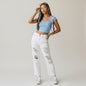 Model wearing Lynn's Closet Boutique Alice + Olivia Genevieve white distressed jeans with a blue crop top.