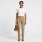 Model wearing Lynn's Closet Boutique beige slim-fit suede trousers with a white t-shirt and brown leather handbag.