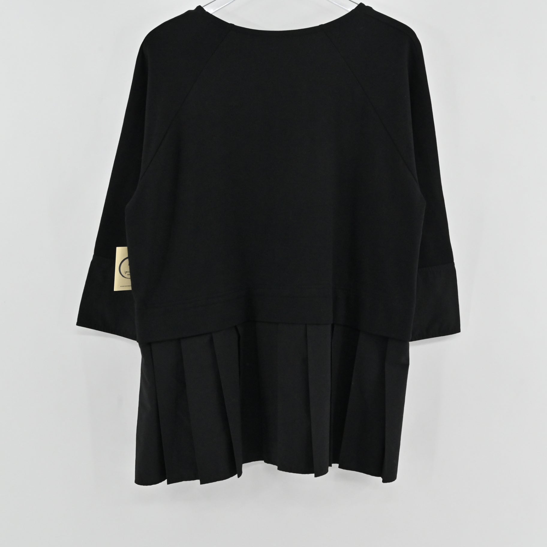 Lynn's Closet Boutique black COS peplum top with three-quarter raglan sleeves and a pleated hem, back view.