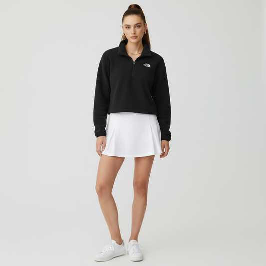 Lynn's Closet Boutique model wearing a black The North Face cropped quarter-zip fleece with a white tennis skirt.
