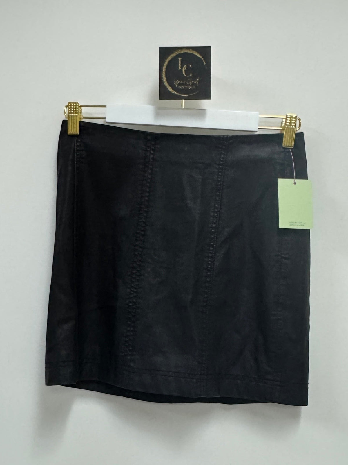 Lynn's Closet Boutique black faux leather mini skirt with panel detailing hanging on a white hanger