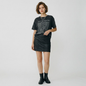 Lynn's Closet Boutique Free People black faux leather mini skirt worn by a model with a graphic tee and ankle boots.