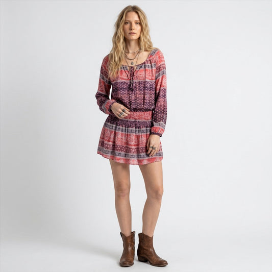 Model wearing a Lynn's Closet Boutique bohemian long sleeve dress with a pink and purple print and tie-neck detail.
