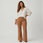 Model wearing Lynn's Closet Boutique Free People camel corduroy flared pants with vertical seams and a white blouse.