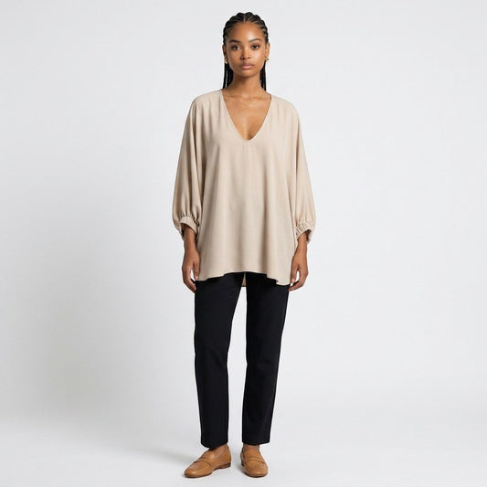 Model wearing a Lynn's Closet Boutique champagne silk V-neck top with billowy sleeves and black trousers