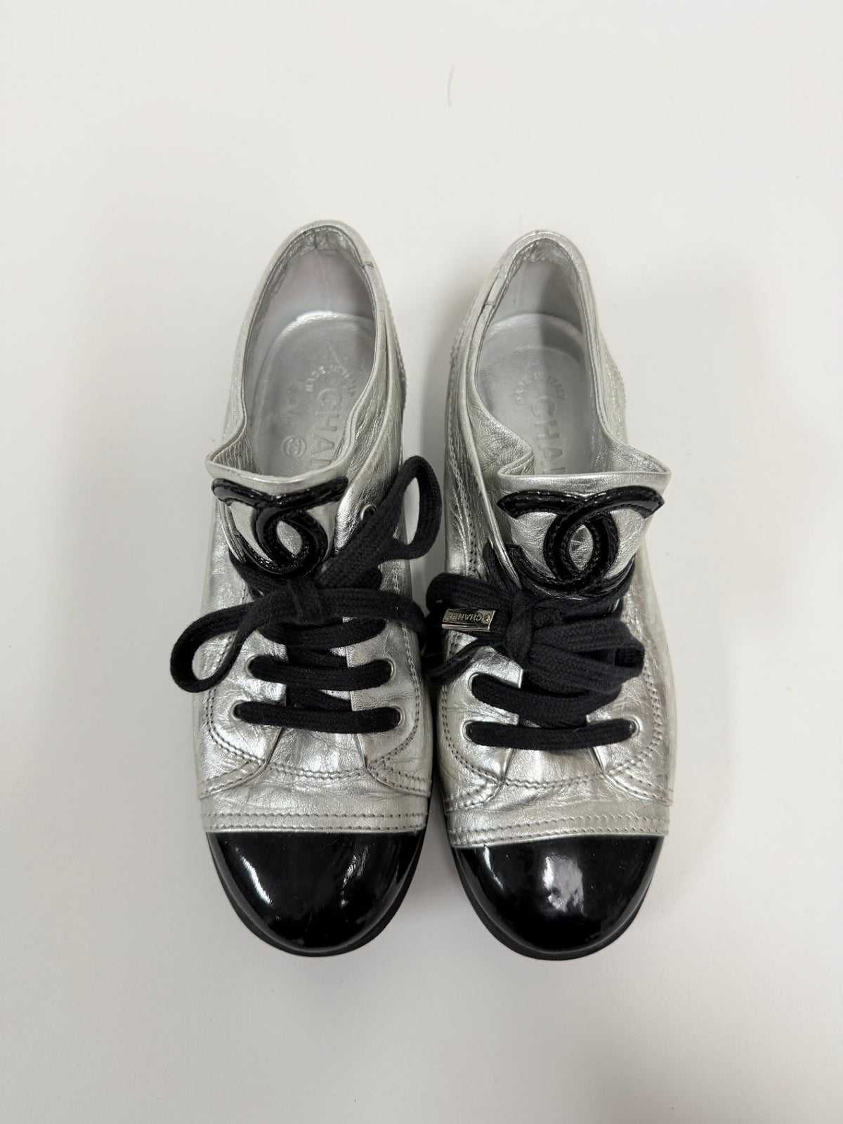 Lynn's Closet Boutique Chanel metallic silver lambskin sneakers with black patent cap toes and CC logo on the tongue.