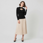 Lynn's Closet Boutique black Chiara Boni long-sleeve top with front cutout worn by a model with a pleated midi skirt