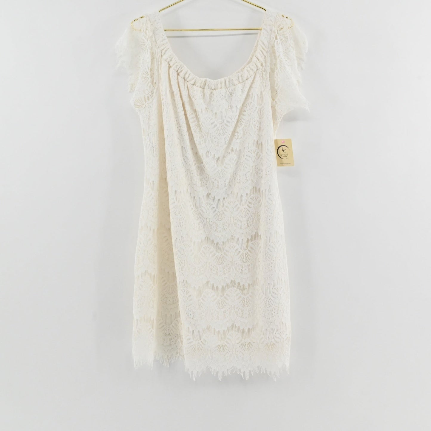 Lynn's Closet Boutique City Chic white lace off-the-shoulder dress with scalloped hem, size 16, hanging on a hanger.