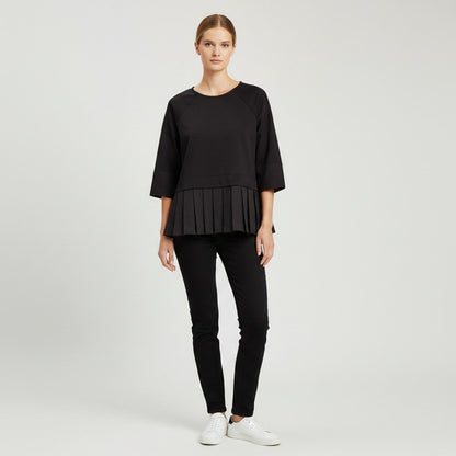 Lynn's Closet Boutique model wearing a black COS peplum top with three-quarter raglan sleeves and pleated hem