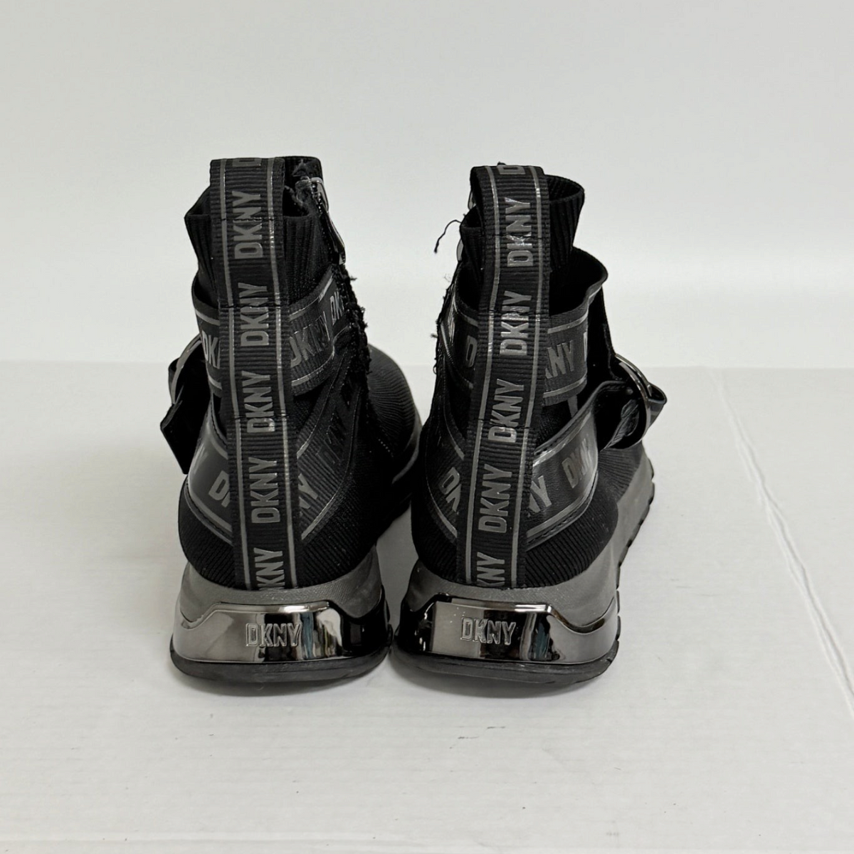 Lynn's Closet Boutique black DKNY Miley high-top sneakers featuring logo-branded heel pulls and lugged rubber outsoles.