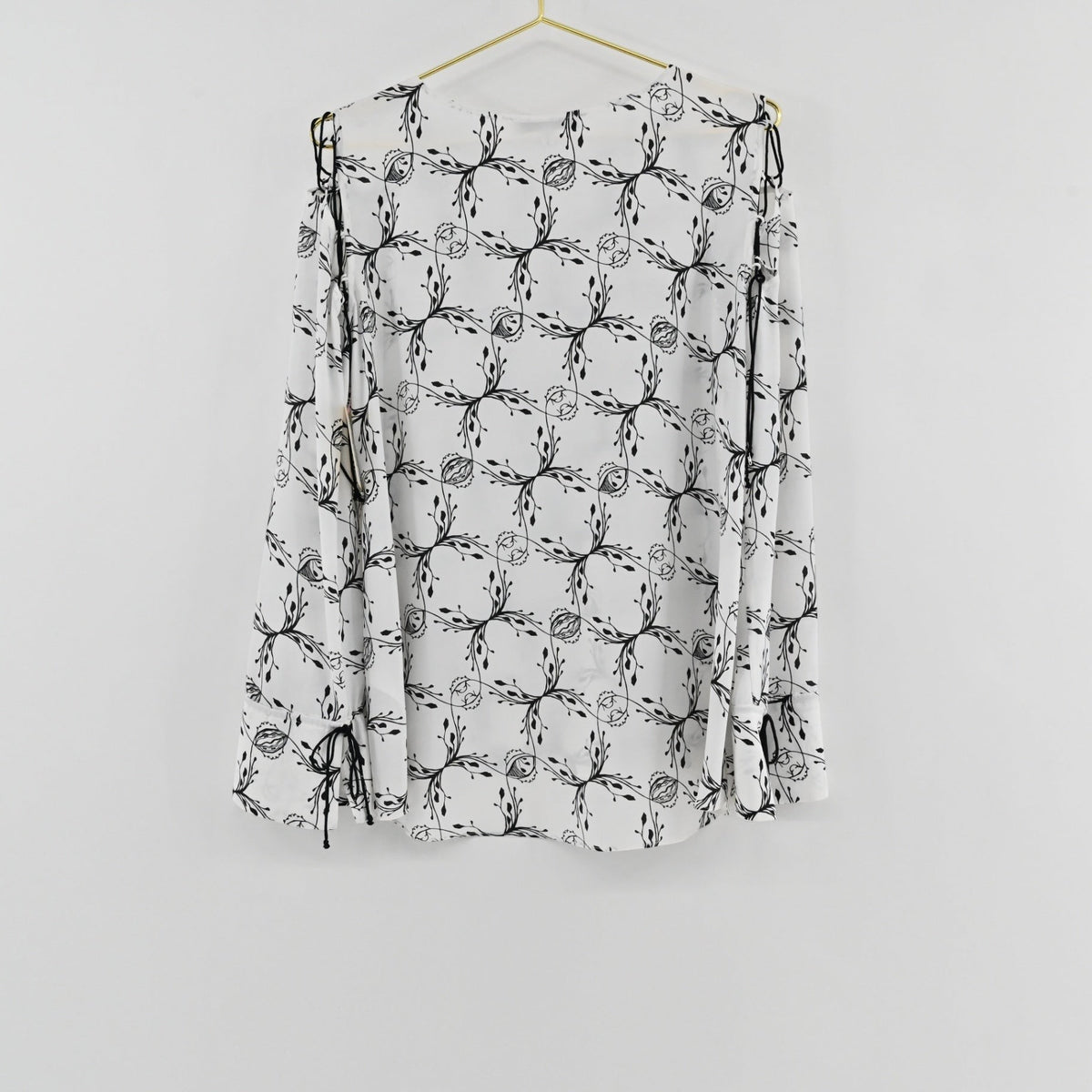 Lynn's Closet Boutique Dorothee Schumacher white top with black botanical print, cold-shoulder cutouts and ribbon ties.