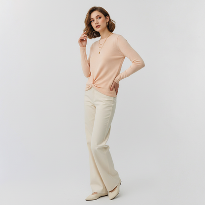 Model wearing Lynn's Closet Boutique DVF Kylee cream long-sleeve sweater with a front twist detail and cream trousers.