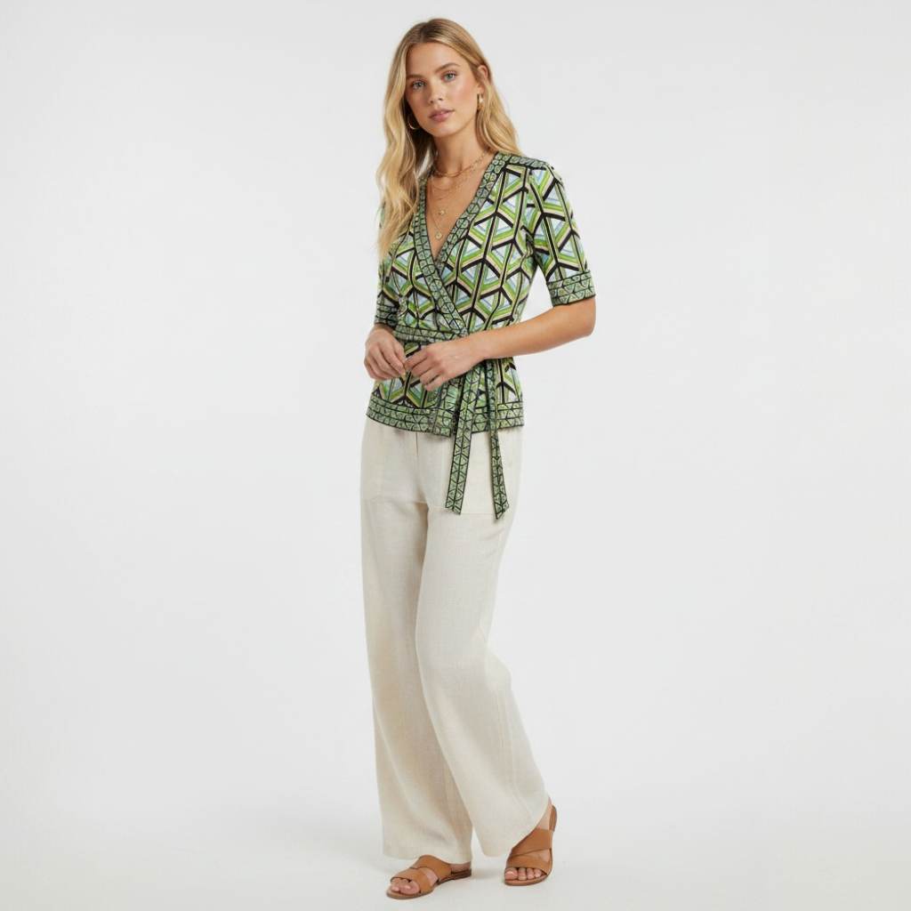 Model wearing a Lynn's Closet Boutique DVF silk wrap top with a green and blue geometric print and tie-waist detail.