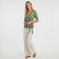 Model wearing a Lynn's Closet Boutique DVF silk wrap top with a green and blue geometric print and tie-waist detail.