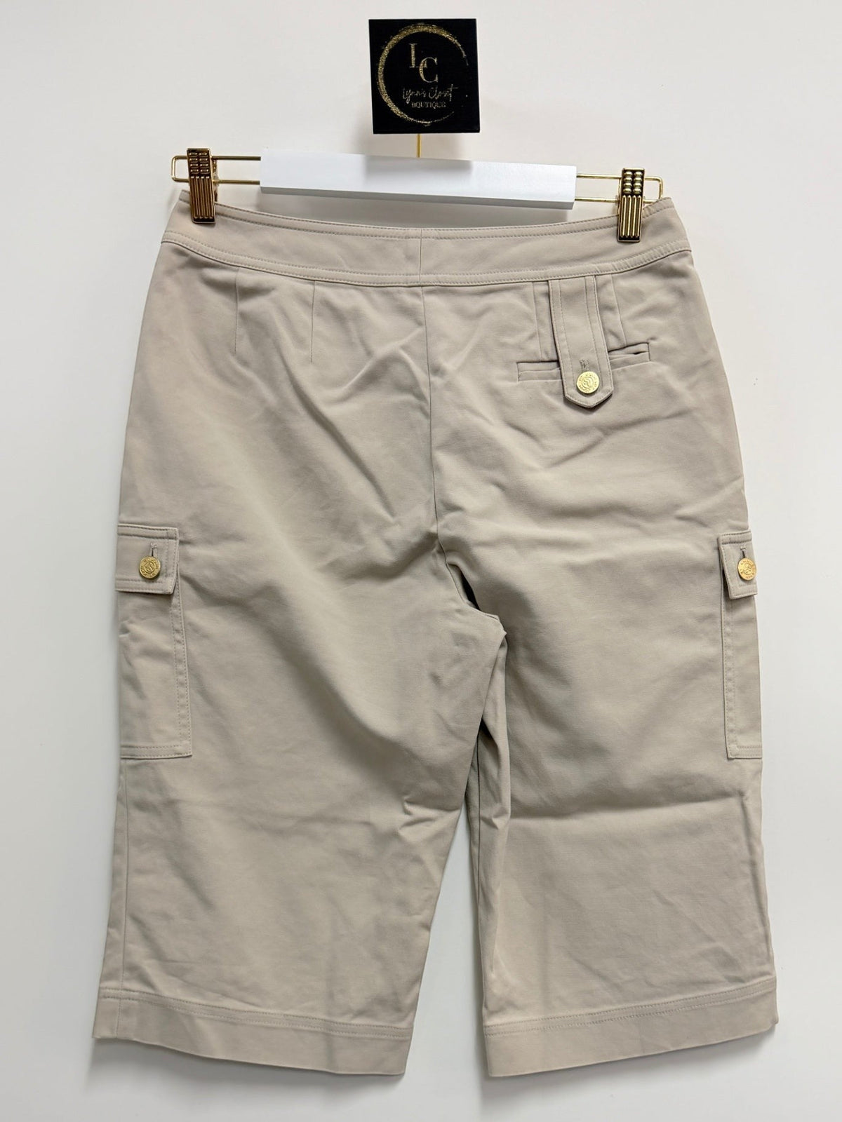 Lynn's Closet Boutique St. John khaki cargo shorts with gold-tone button pockets, back view on hanger.