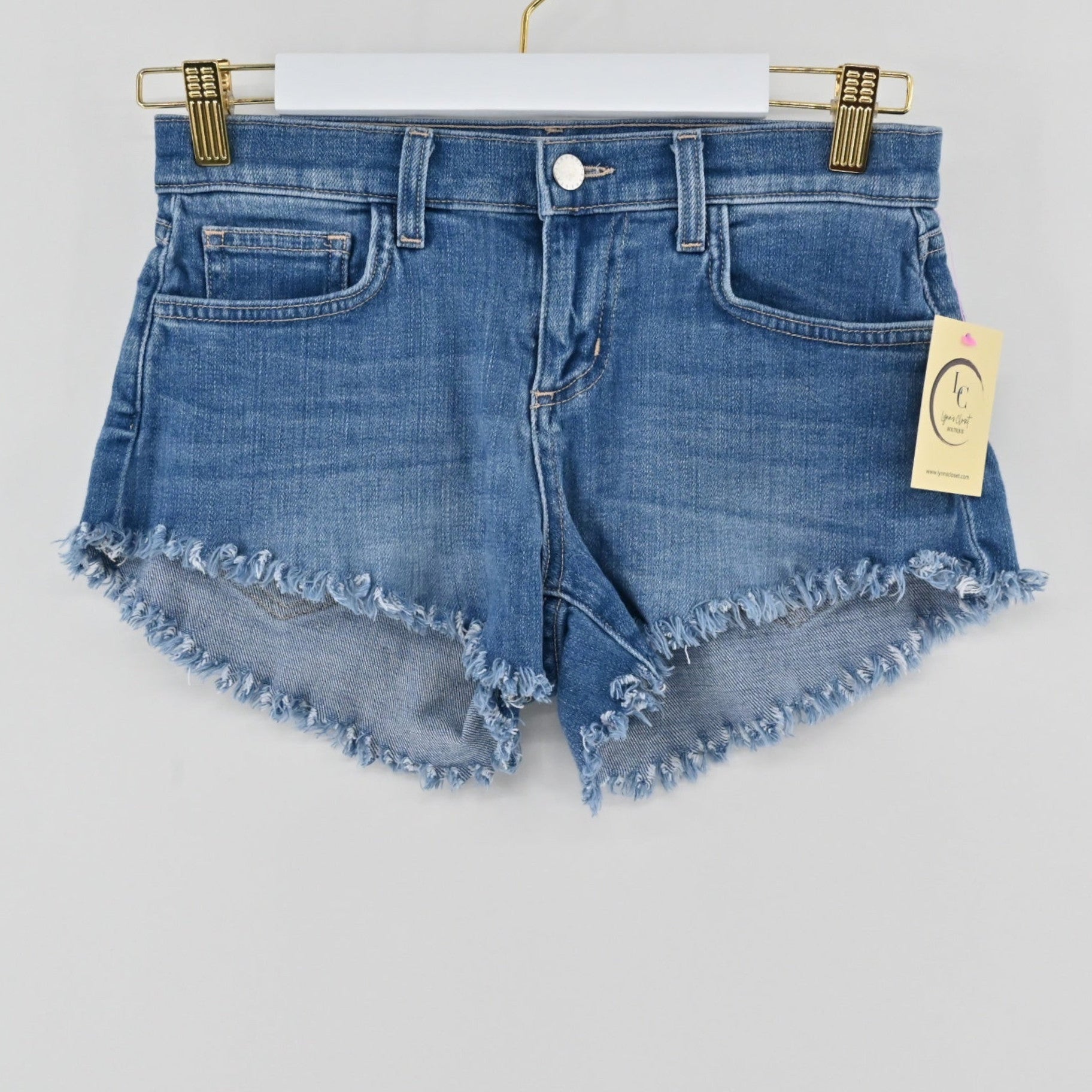 L'Agence Zoe medium-blue denim cut-off shorts with raw hem, available at Lynn's Closet Boutique.