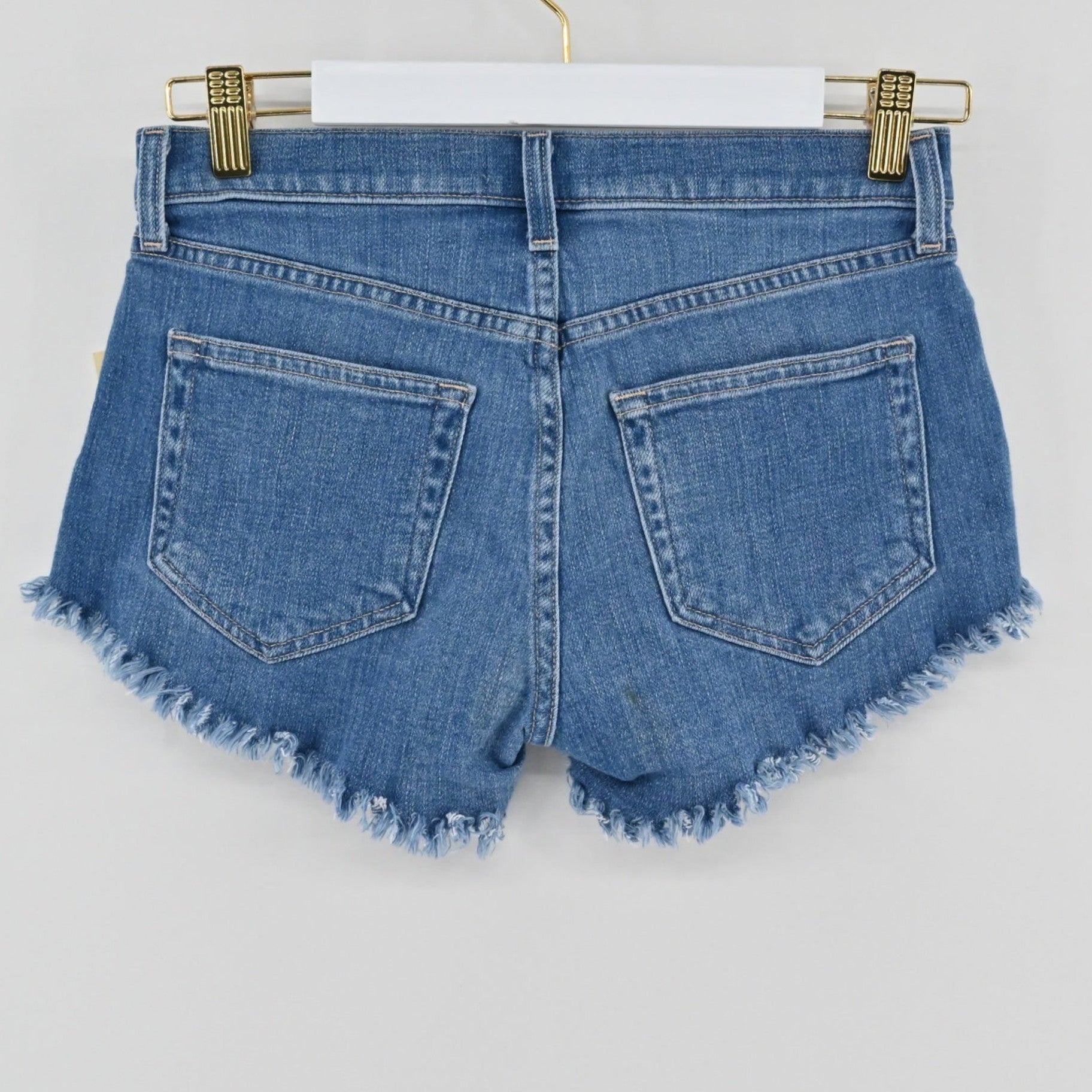 Lynn's Closet Boutique L'Agence Zoe medium-blue denim cut-off shorts with raw-edge hem and five-pocket styling.