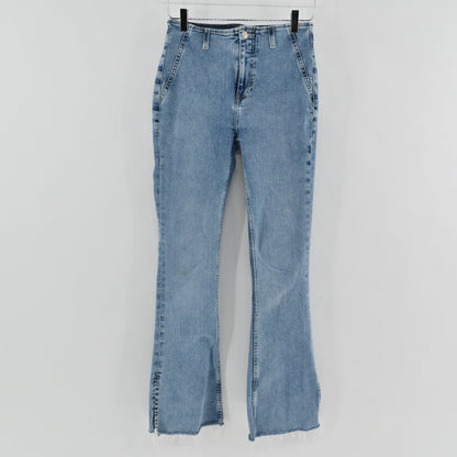 Lynn's Closet Boutique We The Free light wash high-rise flare jeans with a raw split hem hanging on a hanger.