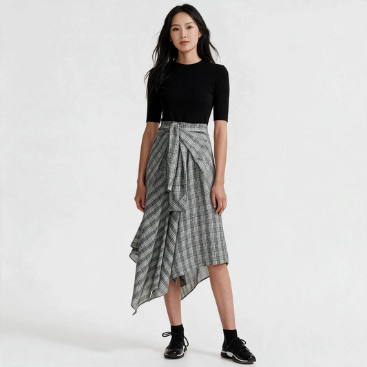 A model wears a Lynn's Closet Boutique Maje midi dress with a black short-sleeve bodice and grey checkered skirt.