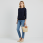Model wearing a Lynn's Closet Boutique navy blue crew neck sweater with blue jeans, espadrilles, and a straw bag.