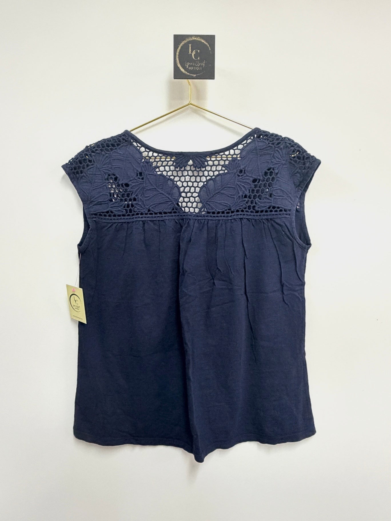 Lynn's Closet Boutique navy sleeveless top with intricate crochet yoke detailing on a gold hanger