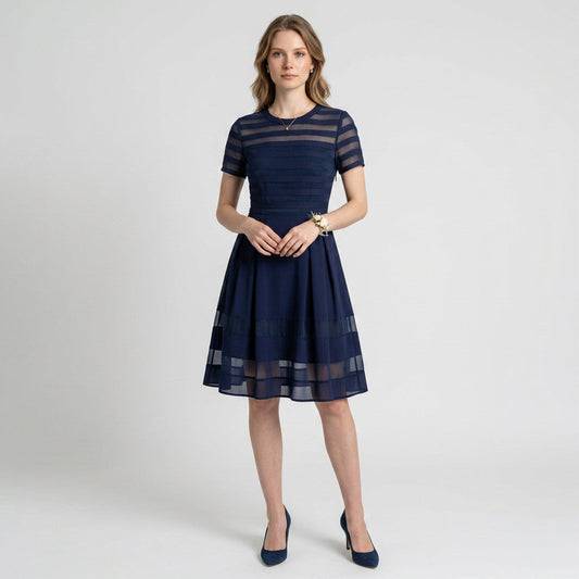 Model wearing a Lynn's Closet Boutique navy Elliatt dress with semi-sheer horizontal striped panels and pleated skirt.