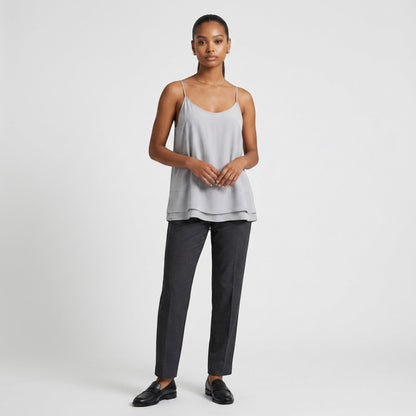Model wearing Lynn's Closet Boutique Nouvelle 95Silk gray camisole with layered hem, spaghetti straps, and dark trousers
