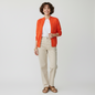 Lynn's Closet Boutique model wearing a vibrant orange St. John Sport zip-up sweater with textured knit chest detail.
