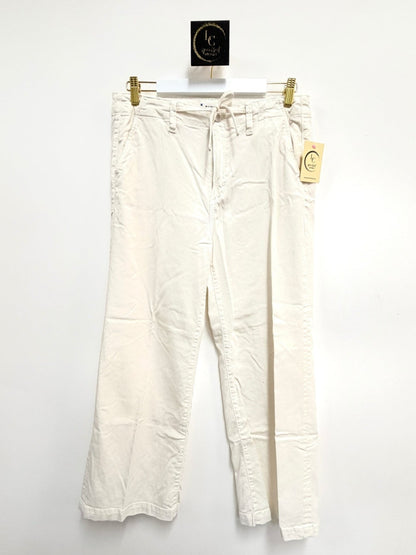 Lynn's Closet Boutique Paige white wide-leg pants with a drawstring waist and pockets hanging against a white wall.