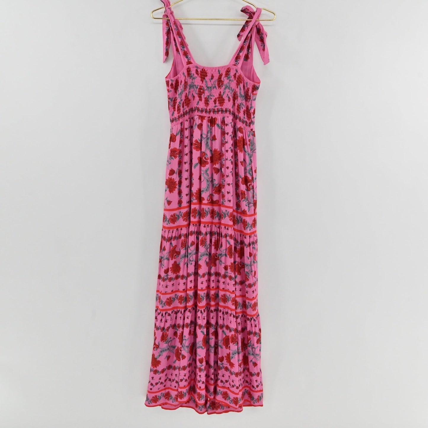 Lynn's Closet Boutique Beach Riot Charlotte pink floral maxi dress with tie straps and a tiered skirt on a hanger.