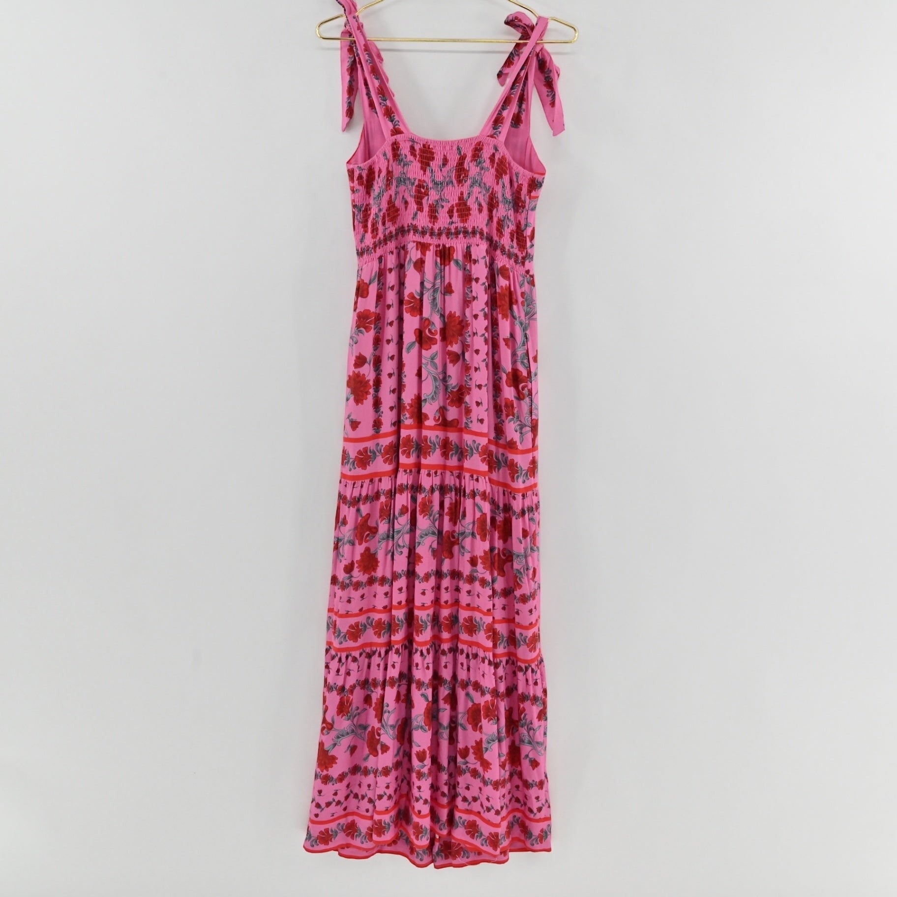 Lynn's Closet Boutique Beach Riot Charlotte pink floral maxi dress with tie straps and a tiered skirt on a hanger.