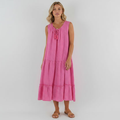 Model wearing a pink sleeveless tiered linen midi dress from Lynn's Closet Boutique with a tassel tie neckline.