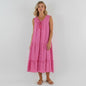 Model wearing a pink sleeveless tiered linen midi dress from Lynn's Closet Boutique with a tassel tie neckline.