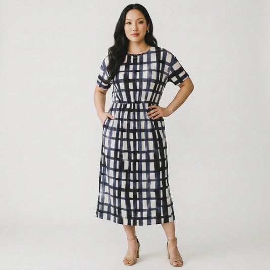 Model wearing a Lynn's Closet Boutique Bitte Kai Rand navy and white grid pleated midi dress with short sleeves.