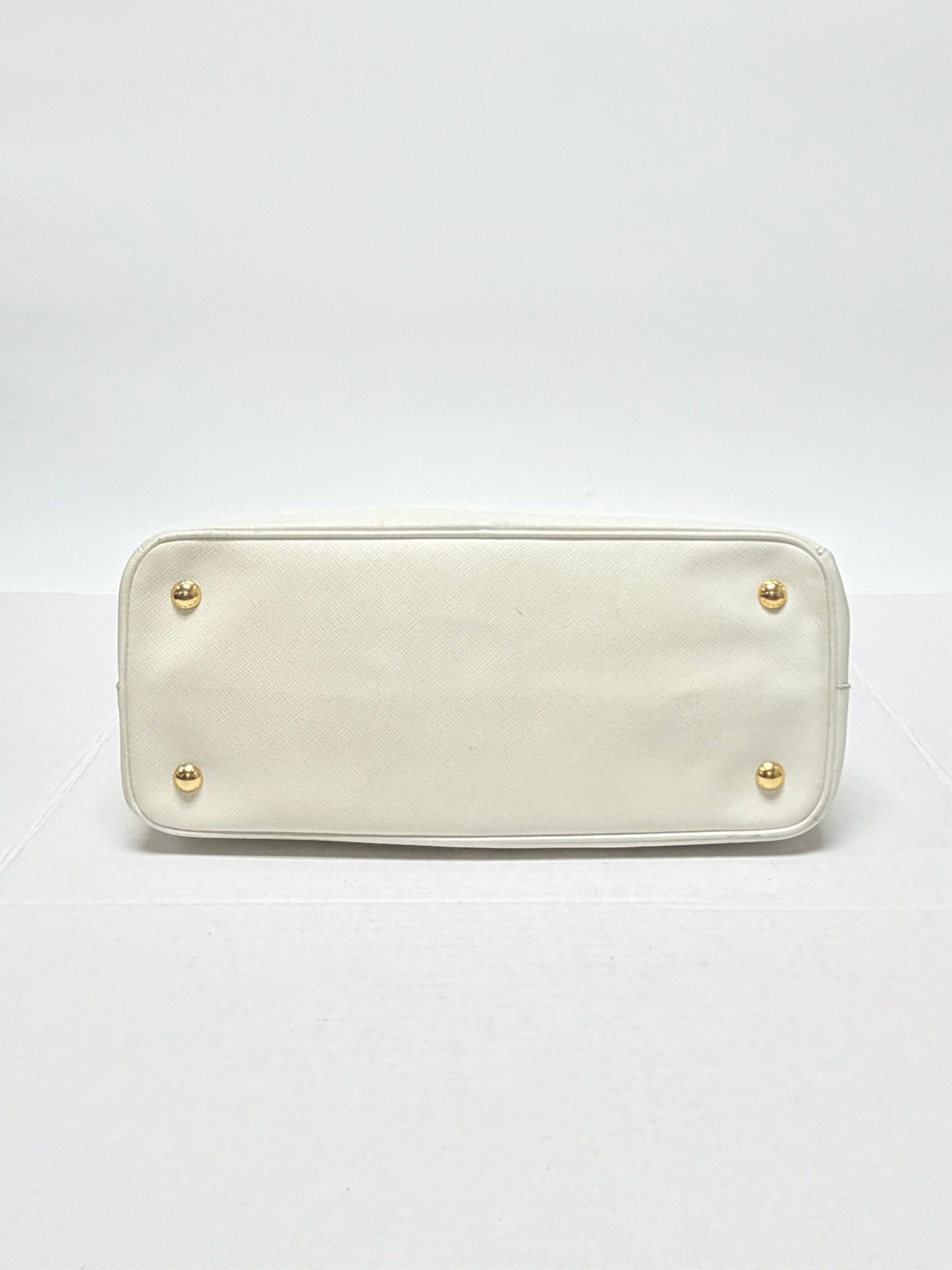 Lynn's Closet Boutique white Prada Galleria Saffiano leather handbag base with four protective gold-tone metal feet.