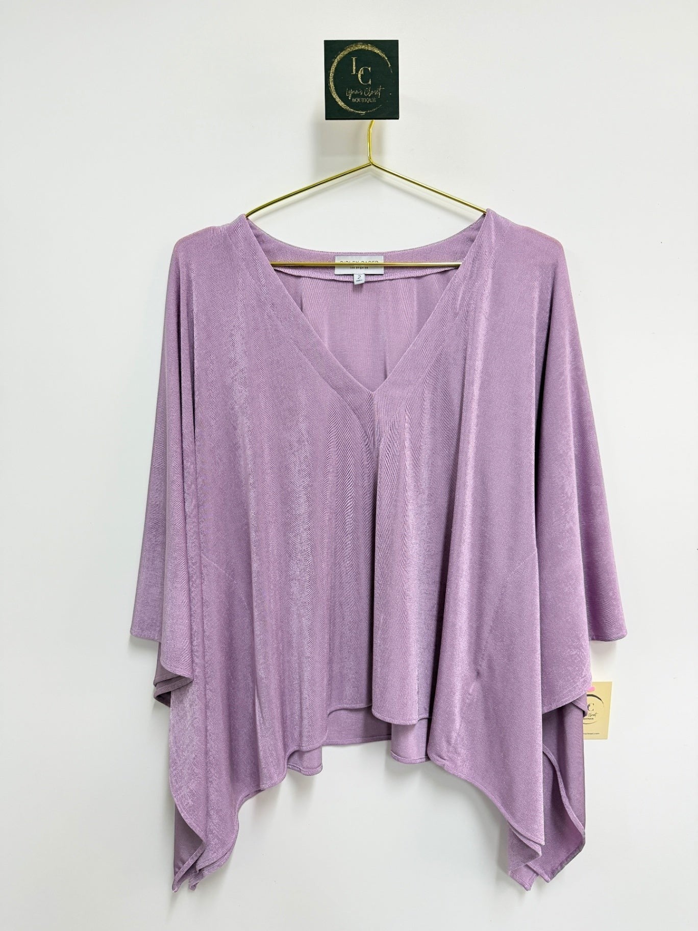 Lynn's Closet Boutique Ripley Rader lilac V-neck flowy top with wide sleeves, hanging on a gold hanger.
