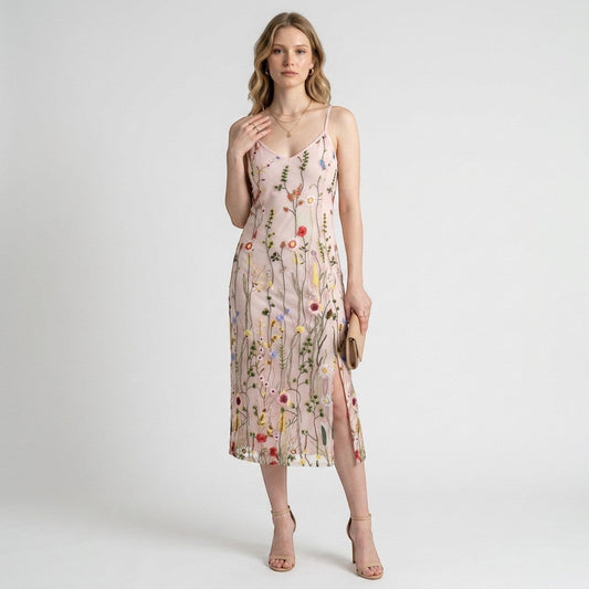 Model wearing a Lynn's Closet Boutique Sam Edelman pink midi dress with colorful floral embroidery and a side slit