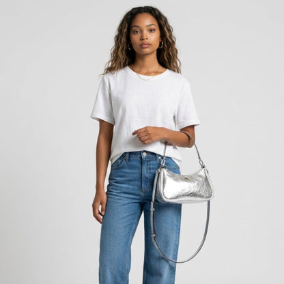Lynn's Closet Boutique model wearing a white t-shirt and jeans holding a silver crinkle metallic Kate Spade bag