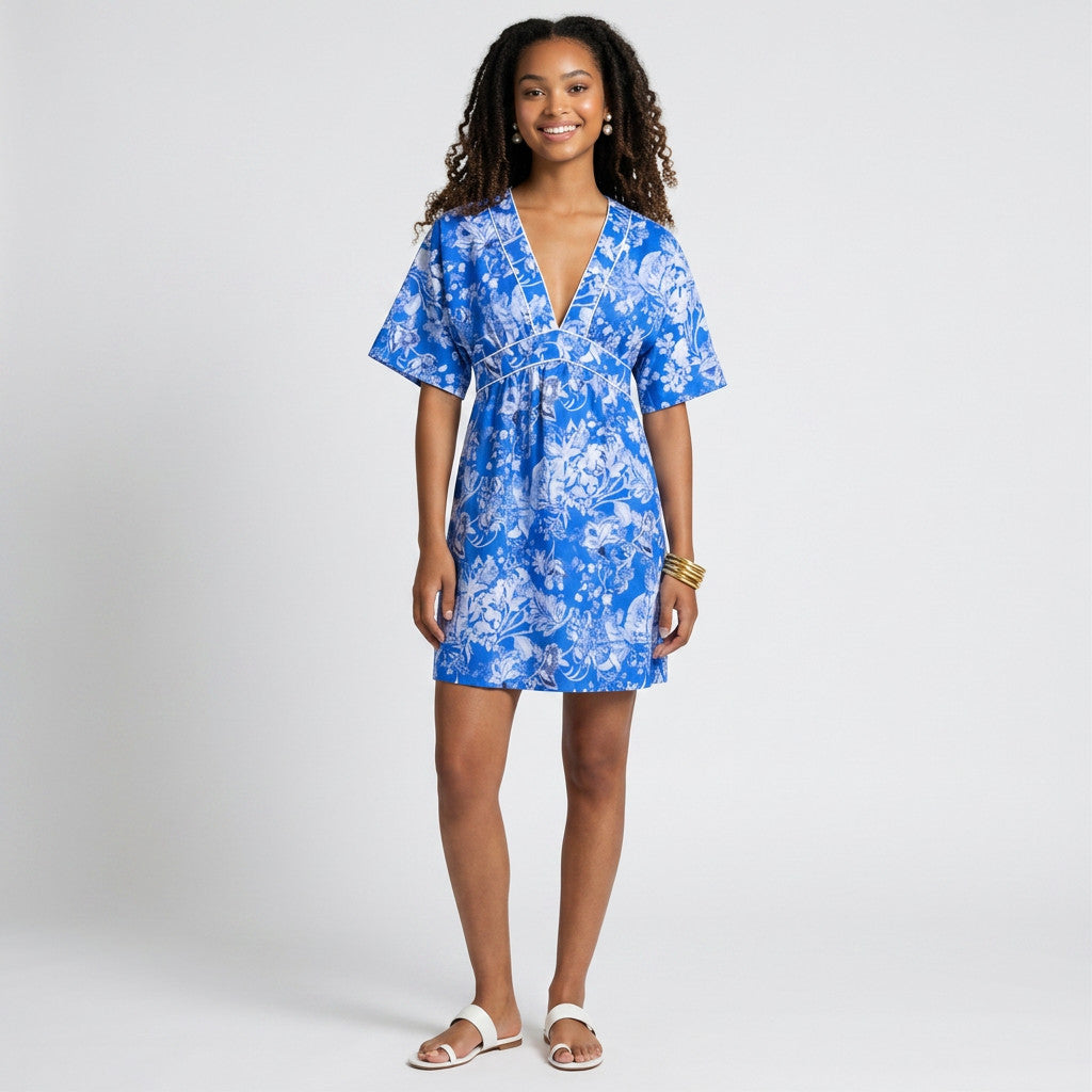 A model wearing a Lynn's Closet Boutique Socapri blue and white floral silk V-neck dress with white piping detail.