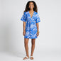 A model wearing a Lynn's Closet Boutique Socapri blue and white floral silk V-neck dress with white piping detail.