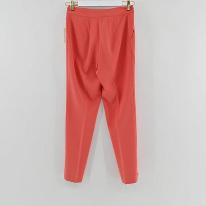 Lynn's Closet Boutique St. John coral slim-leg trousers hanging on a hanger, featuring a clean waistband and creases.