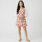 Lynn's Closet Boutique model wearing a Tanya Taylor red and cream plaid V-neck dress with white puff sleeves