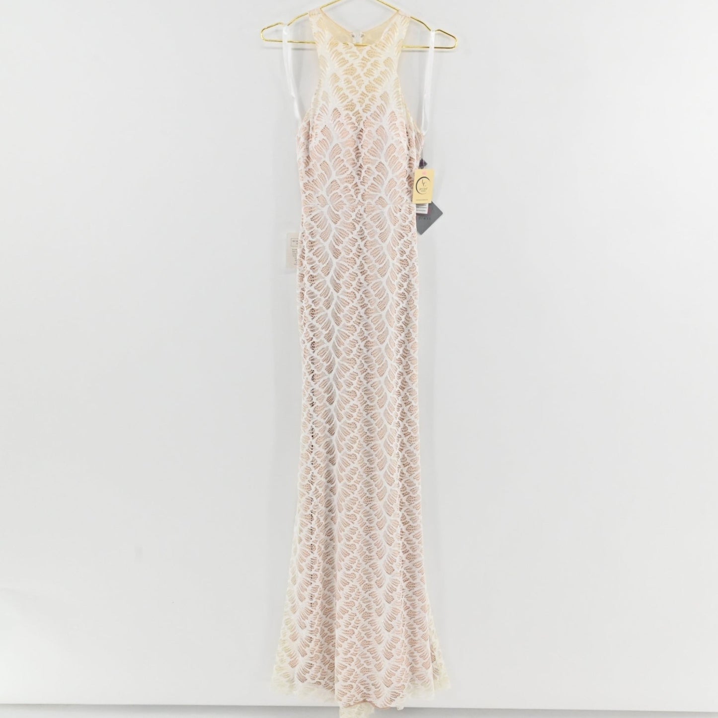 Lynn's Closet Boutique white floor-length lace gown with a high-neck racerback design and intricate leaf-pattern overlay.