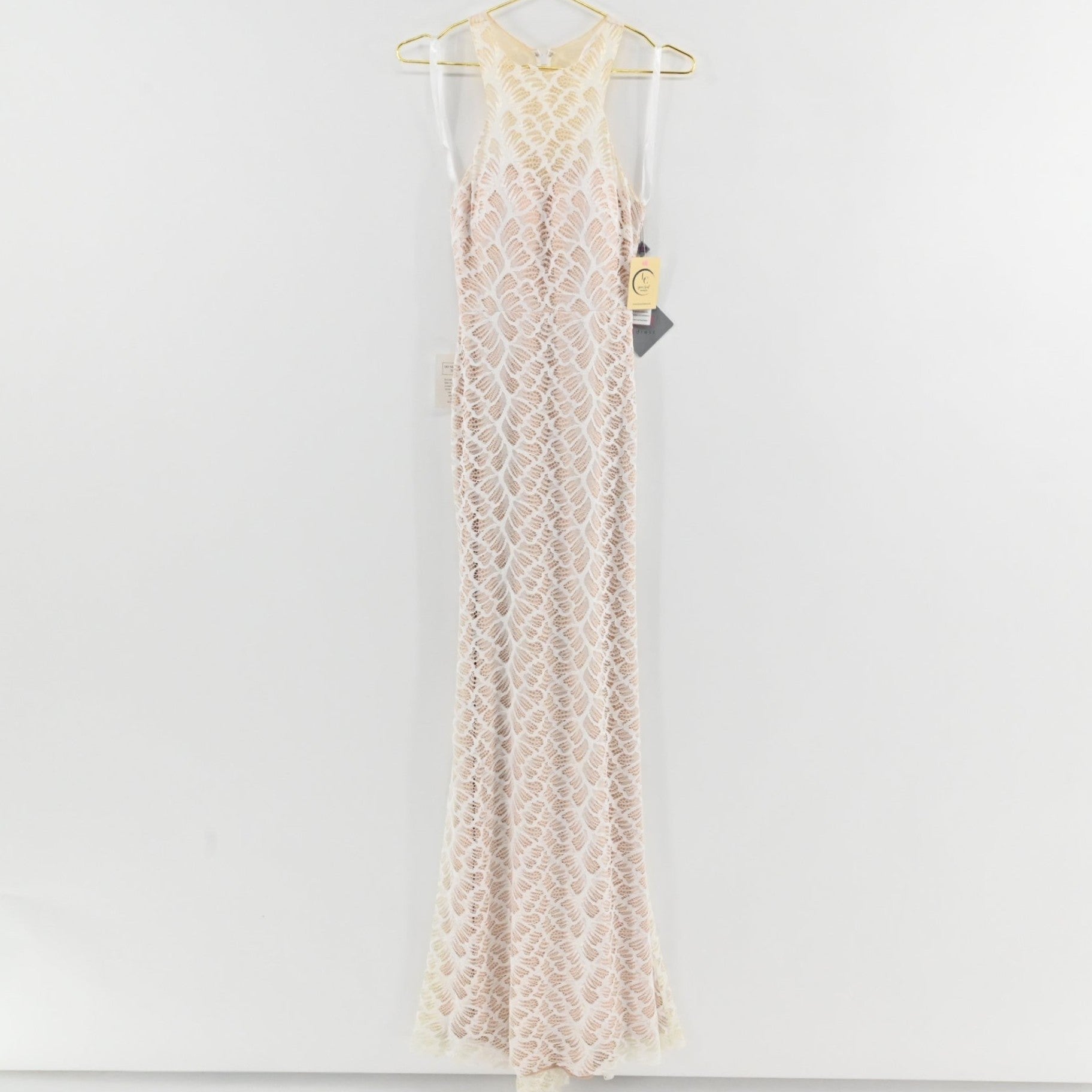 Lynn's Closet Boutique white floor-length lace gown with a high-neck racerback design and intricate leaf-pattern overlay.