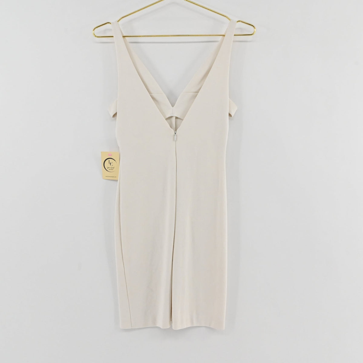 Lynn's Closet Boutique white Amanda Uprichard mini dress with deep V-neck and cold-shoulder detail on a gold hanger