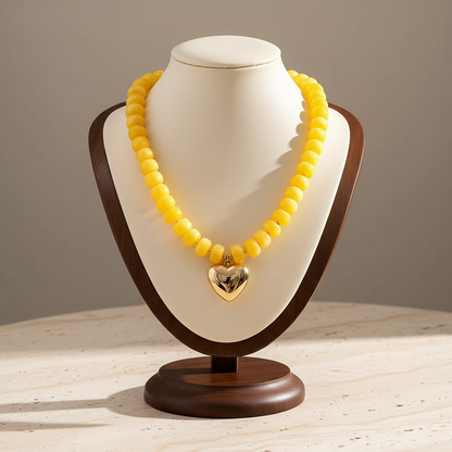 Lynn's Closet Boutique yellow chunky acrylic bead necklace with a polished gold-tone heart pendant on a display bust