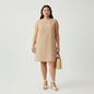 Model wearing a sleeveless camel Emanuel Ungaro shift dress from Lynn's Closet Boutique with a straw tote bag.